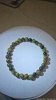 Top-down image of the natural green jade and tiger's eye bead bracelet showing bead color and arrangement.
