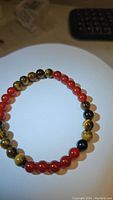 Photo of round polished fire red-orange carnelian and tiger’s eye beads on a stretchy bracelet, showing bead color and pattern.