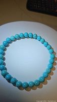 Natural turquoise bead bracelet laid out in a circle on a white surface, showing the robin's egg blue beads with slight natural matrix inclusions.