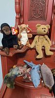 Photo showing seven Beanie Babies including a black bear, a beige dog, a light brown bear, and various marine animals like a dolphin and whale. All with visible TY hang tags.