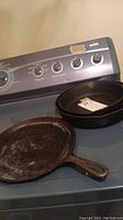 Two cast iron frying pans placed on stove surface.
