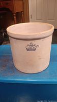 Front view of beige stoneware crock with blue crown and number 2 design.