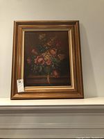 Framed floral oil painting showing a bouquet of flowers in a gold-tinted brown frame.
