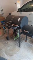 Master Built charcoal grill with curved lid, thermometer, utensils on front shelf and large main cooking chamber.