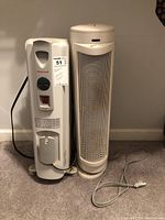 Two heaters side by side on carpeted floor: a Honeywell oil-filled radiator heater and a Bionaire tower ceramic heater.