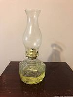 Front view of vintage glass oil lamp with chimney and yellow liquid in base