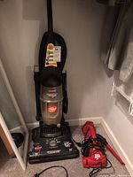 Full view of Bissell PowerForce upright vacuum cleaner with Dirt Devil Ultra handheld vacuum cleaner on floor beside it.