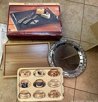 Original box and components of the 8-piece Wine Enthusiasts marble cheese board set with three serving trays arranged around it.