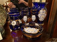 Wide angle showing all items: two blue floral vases, two candle sticks, and lidded dish with matching design