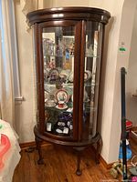Front view of cherry wood display cabinet filled with decorative dishes