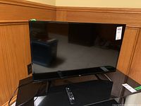 Front view of 32-inch Amazon Fire TV set on black media stand, powered off.