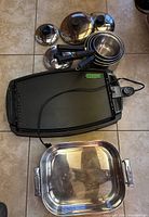 Top view showing black Beaumark electric griddle, four nested Lagostina stainless steel pots with lids, and Cuisinox stainless steel roasting pan