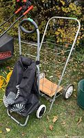Two aluminum grocery carts with black fabric bags on a grassy outdoor surface near garden pots.