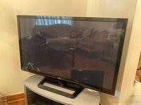 Front view of LG Plasma TV showing screen and stand in a living room setting.
