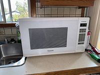 Front view of white Panasonic microwave showing control panel and windowed door.