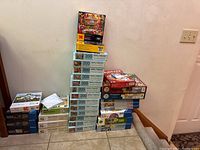 Photo showing the full lot of puzzles stacked in three columns with some other games visible on the side including Yahtzee and cards in plastic bag
