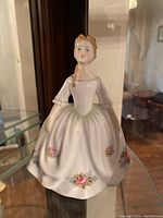 Front view of Royal Doulton porcelain figurine of a woman in white dress with floral designs.