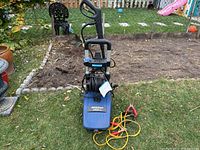 Full view of blue Simoniz electric power washer with booster cables connected and coiled on the handle.