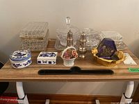 Various glass and ceramic trinket boxes and dishes, artwork includes Delft style ceramics and glass items with decorative patterns and gold accents.