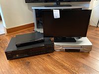 Photo showing the Panasonic VCR, Sony DVD player, and Pioneer CD player stacked on the floor alongside the Insignia TV.