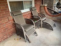 Two brown metal framed patio chairs with mesh seats and backs and cushioned headrests, shown on a covered porch.