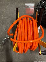 Top view of bright orange 3/8 air hose coiled on yellow metal reel.