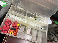Open plastic case showing red, orange, yellow and black wire connectors, white zip ties, and small metal fittings in compartments