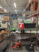 Full front view of the industrial metal wire shelving rack with multiple shelves loaded with miscellaneous items.