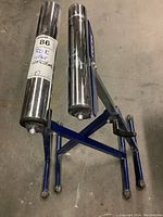 Angle view of one ROK roller work stand folded, showing blue frame and dual chrome rollers.