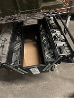 Metal toolbox open with three expandable trays filled with many chrome sockets of different sizes and types on a storage rack.