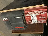 Sony 222W Xplod amplifier and MTX Audio TC4001 Thunder Class-D amplifier side by side on a wooden surface.