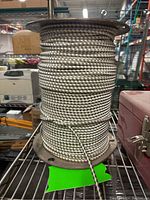 Close-up of a large metal spool holding black and white braided cording.