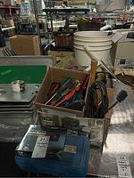 Wide view of lot showing box of assorted screwdrivers, electrical cords, white bucket, metal trays, and toolbox.
