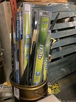 Metal bucket filled with assorted windshield wiper blades in various sealed packs and loose blades including I Klear 28 inch blades and Proform packages.