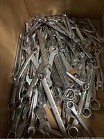 Photo of a box filled with various chrome combination wrenches showing open and box ends, marked with various metric and imperial sizes