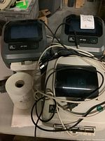 Two Zebra ZP 505 printers visible at rear with clear flip-top lids and front status indicators alongside beige LP 2844 printer and a roll of label paper.