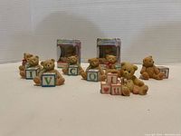 Front view of nine Cherished Teddy figurines with colorful letter blocks, some in original boxes, arranged on white background