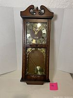 Full view of Daniel and Dakota quartz wall clock with Westminster chime and pendulum, featuring traditional wooden case and Roman numeral dial.