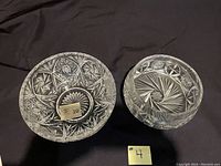 Two clear crystal bowls side by side on dark cloth showing intricate cut designs and Bohemia labels.