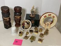 Full lot shot showing two wooden carved head statues, Boyd's bear figurine in box, twelve small metal décor pieces including miniature teapots and other brass items, a decorative ring with teddy bear, and a white bell.