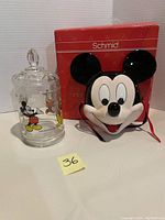 Photo showing Mickey Mouse glass jar with lid and Mickey Mouse mask with original red Schmid box behind.