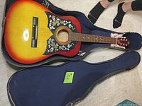 Sunburst acoustic guitar laid in navy blue padded gig bag