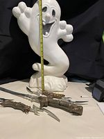 Photo showing light-up plastic ghost decoration about 24 inches tall with playful pose and raised arms, and three costume swords with various blade shapes and ornate handles.