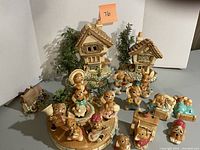 Photo showing set of 19 Pendelfin ceramic bunny figurines posed around two small ceramic cottages with trees, arranged on a round wooden platform.