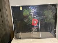 New 24x30 black shadow box frame sealed in packaging with label showing use for sports jerseys and memorabilia.
