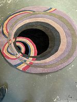 Top view of the round wool rug showing its concentric circles and colorful stripes.