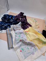 Photo showing five assorted vintage scarves with various colors and patterns including floral and stripes.