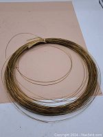 Full coil of brass wire, showing the whole item laid flat with natural wear visible.