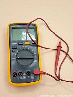 Front view of the Fluke 18B+ digital multimeter with red test leads connected and rotary switch visible.