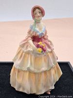 Front view of the Royal Doulton porcelain figurine "Irene," showing detailed painted layers of the dress and bonnet, with flowers in hand.